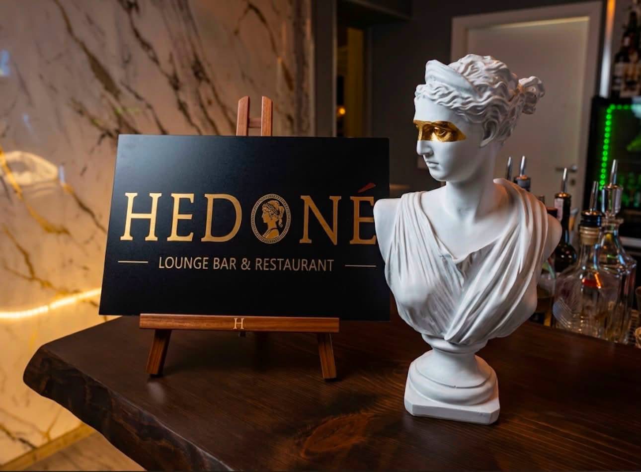 Il busto della dea Hedoné accanto all'insegna del locale